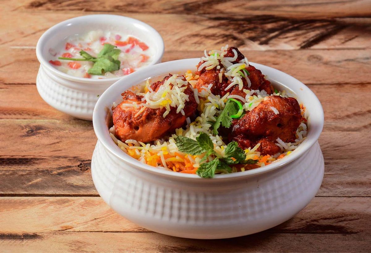 Flavorful chicken biryani with raita in a bowl